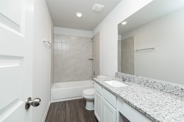 full bathroom with tiled shower / bath, hardwood / wood-style floors, vanity, and toilet