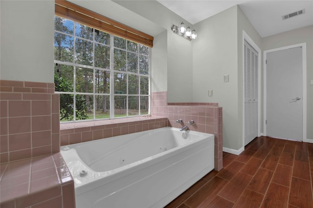 bathroom featuring tiled bath and hardwood / wood-style floors