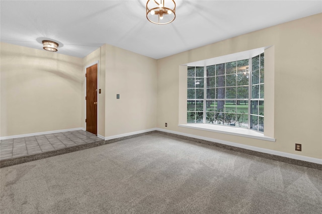 unfurnished room featuring a notable chandelier and carpet