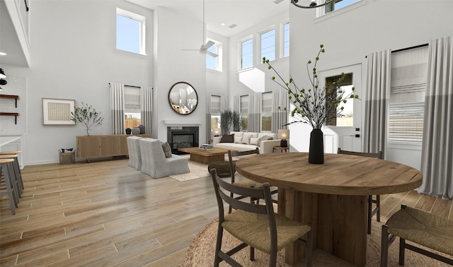 dining room featuring a wealth of natural light, a towering ceiling, and light wood-type flooring