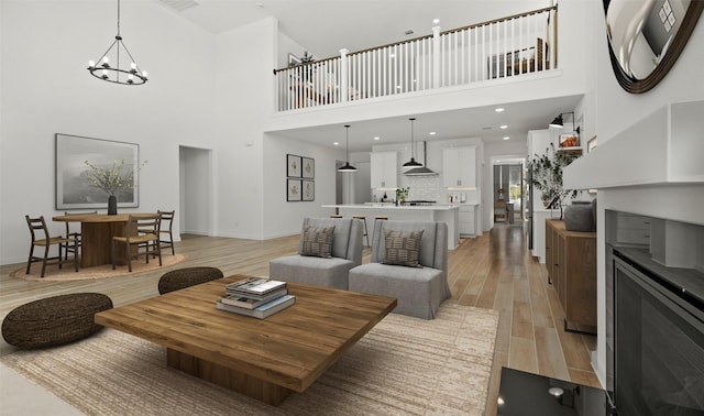 living room with a notable chandelier, a high ceiling, and light wood-type flooring