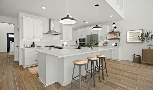 kitchen with white cabinets, wall chimney range hood, sink, and appliances with stainless steel finishes