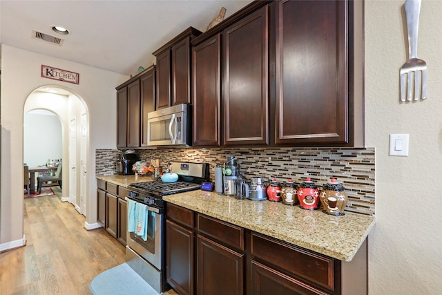 13423 Astley Acres Ln, Cypress, TX 77429 - kitchen with visible vents, arched walkways, light wood-style floors, tasteful backsplash, and appliances with stainless steel finishes