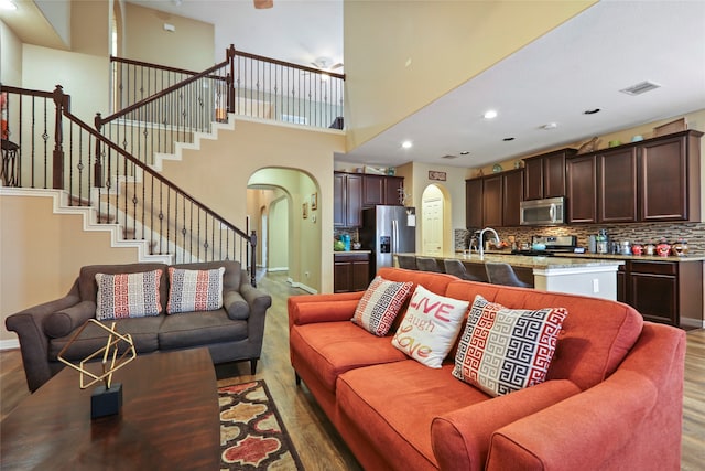 living room featuring a towering ceiling, hardwood / wood-style floors, and sink