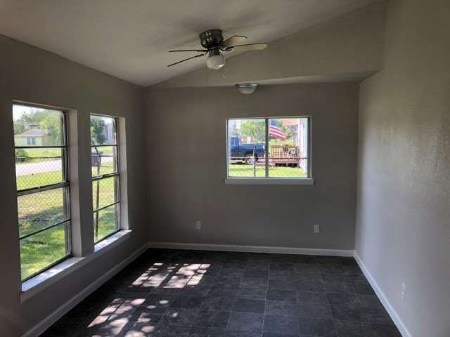 spare room with lofted ceiling, ceiling fan, and plenty of natural light