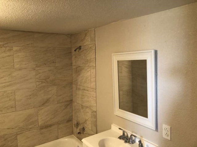 bathroom featuring tiled shower / bath combo, a textured ceiling, and sink