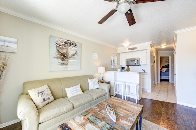 living room with ceiling fan, dark hardwood / wood-style floors, crown molding, and a textured ceiling