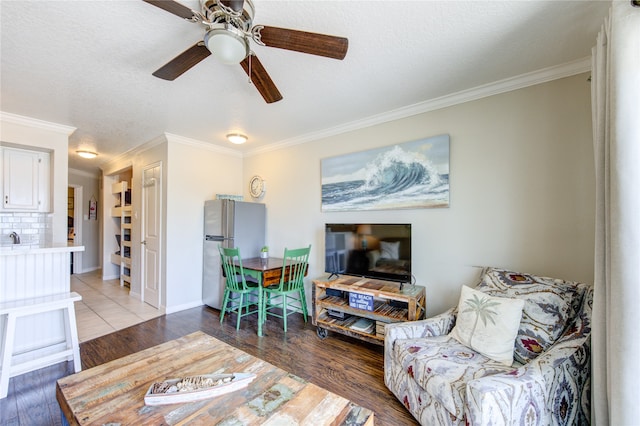 living room featuring ceiling fan, hardwood / wood-style flooring, crown molding, and a textured ceiling