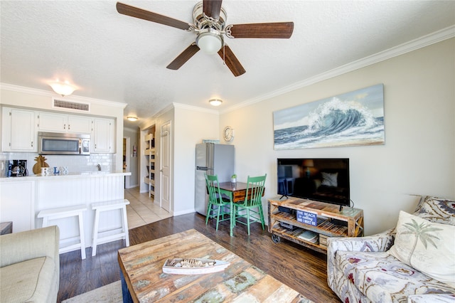 living room featuring ornamental molding, dark hardwood / wood-style flooring, ceiling fan, and a textured ceiling