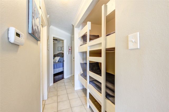 interior space featuring light tile patterned floors, crown molding, and a textured ceiling