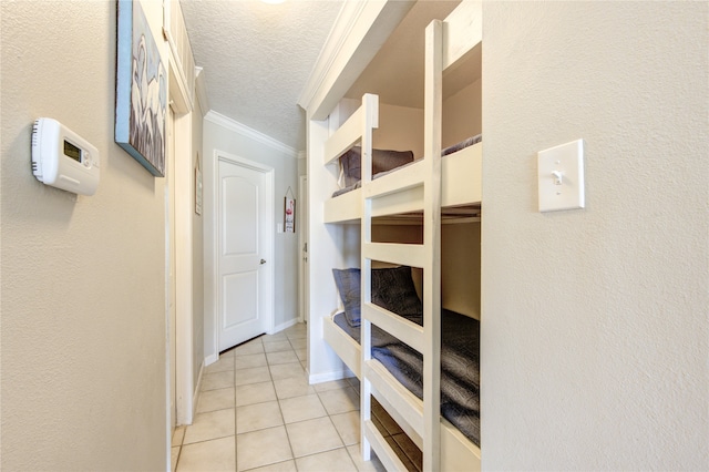 mudroom with ornamental molding, a textured ceiling, and light tile patterned floors