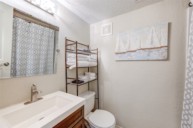 bathroom featuring vanity, toilet, and a textured ceiling