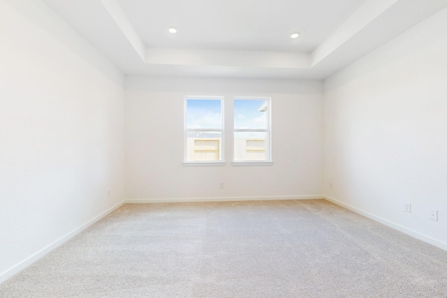 unfurnished room with light carpet, recessed lighting, a raised ceiling, and baseboards