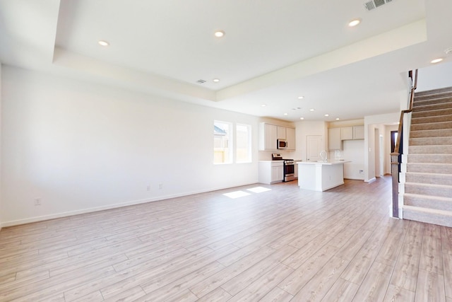 unfurnished living room featuring light wood-type flooring, recessed lighting, baseboards, and stairs