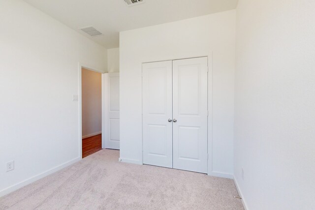 unfurnished bedroom with light carpet and a closet