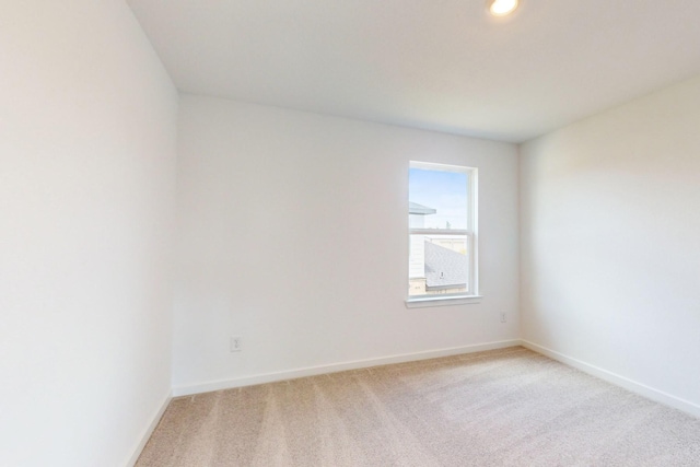 empty room featuring light carpet and baseboards