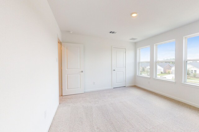 unfurnished bedroom with light carpet and multiple windows