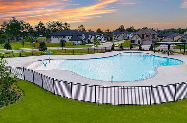 pool at dusk featuring a yard and a patio