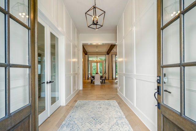 entrance foyer with light hardwood / wood-style flooring, a chandelier, and french doors