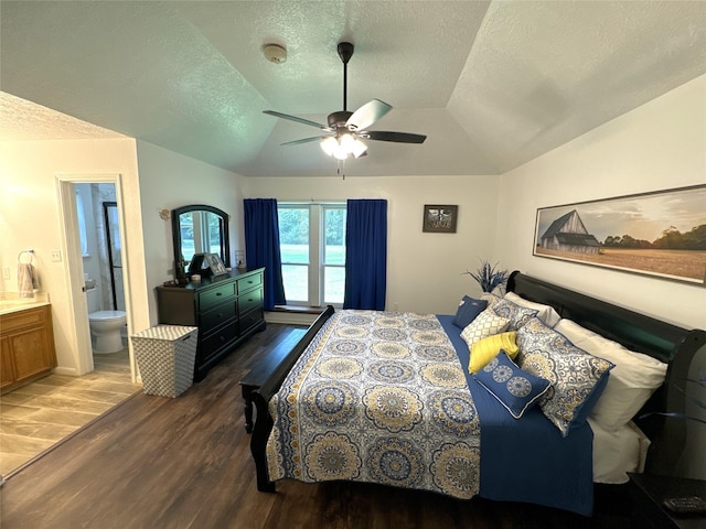 bedroom featuring vaulted ceiling, dark hardwood / wood-style floors, ensuite bath, and ceiling fan