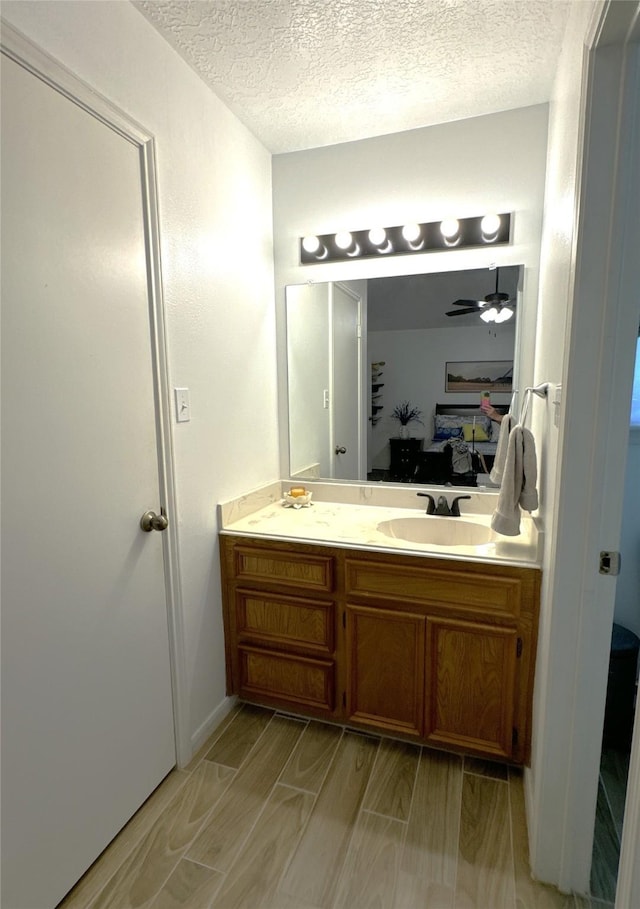 bathroom featuring ceiling fan, hardwood / wood-style floors, vanity, and a textured ceiling