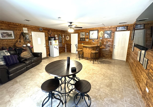 living room with bar, ceiling fan, and brick wall