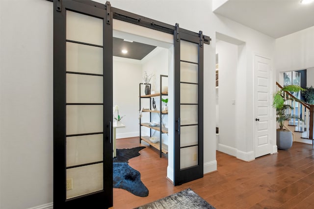 interior space with ornamental molding, wood-type flooring, and a barn door