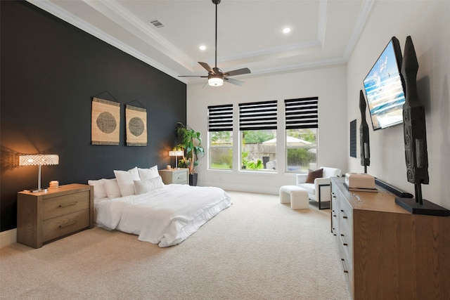 carpeted bedroom with ornamental molding, ceiling fan, and a raised ceiling