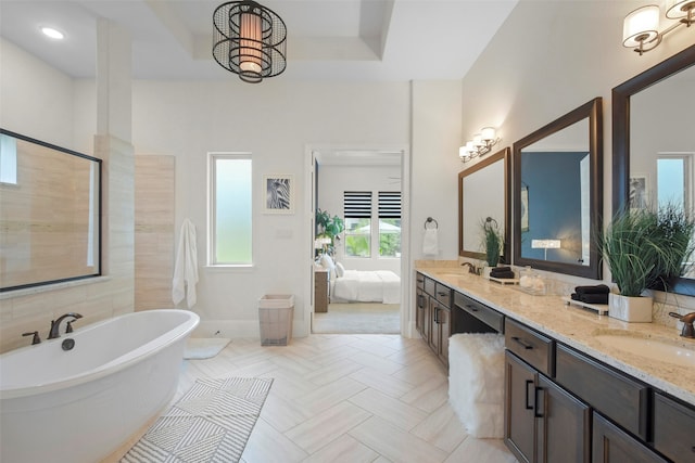 bathroom with a wealth of natural light, a tub to relax in, and vanity