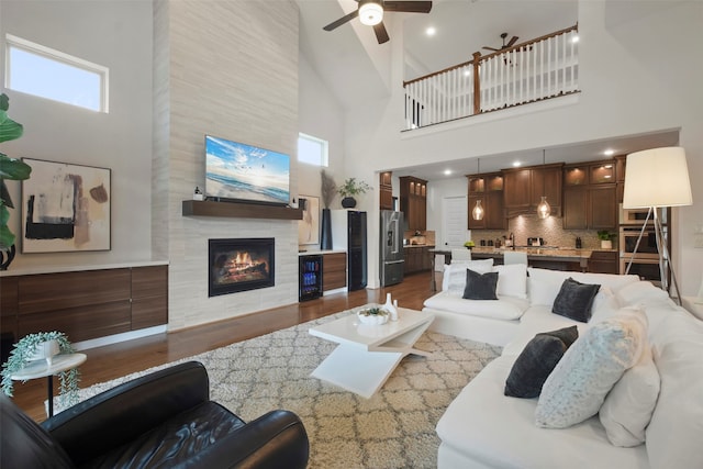 living room featuring high vaulted ceiling, dark wood-type flooring, ceiling fan, and a fireplace