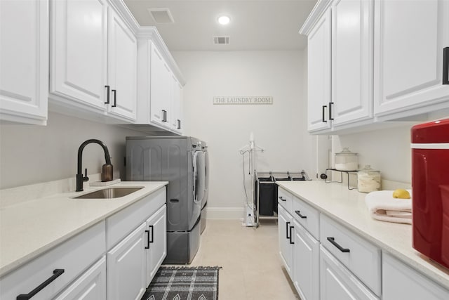 laundry area with cabinets, washing machine and dryer, and sink