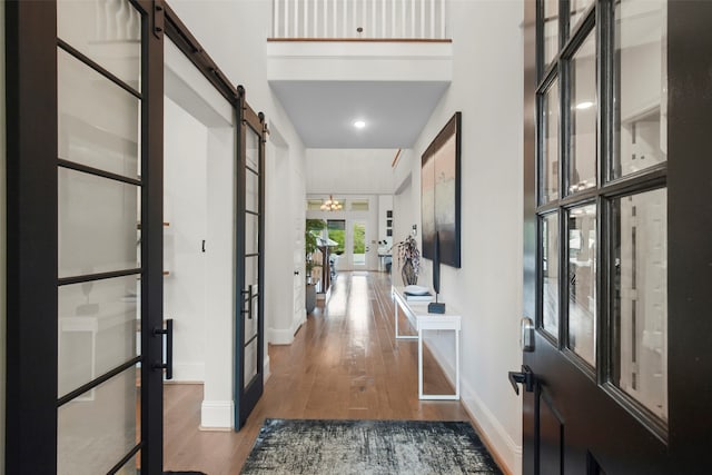 entrance foyer featuring wood-type flooring, french doors, a barn door, and a high ceiling