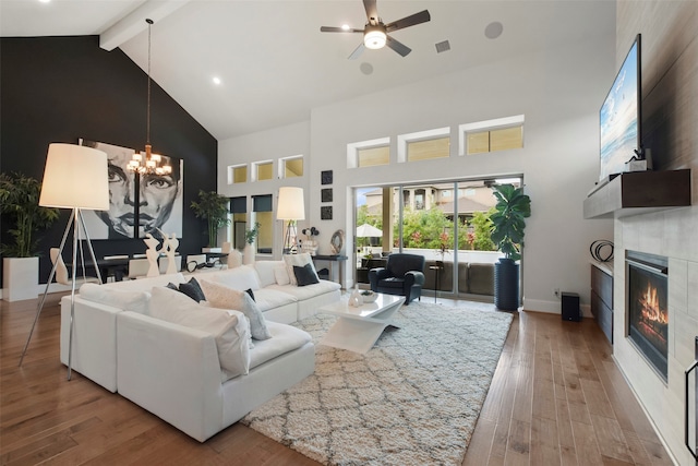 living room featuring wood-type flooring, ceiling fan with notable chandelier, beam ceiling, high vaulted ceiling, and a large fireplace