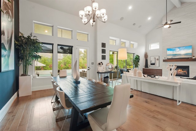 dining space featuring ceiling fan with notable chandelier, light hardwood / wood-style floors, beamed ceiling, and high vaulted ceiling