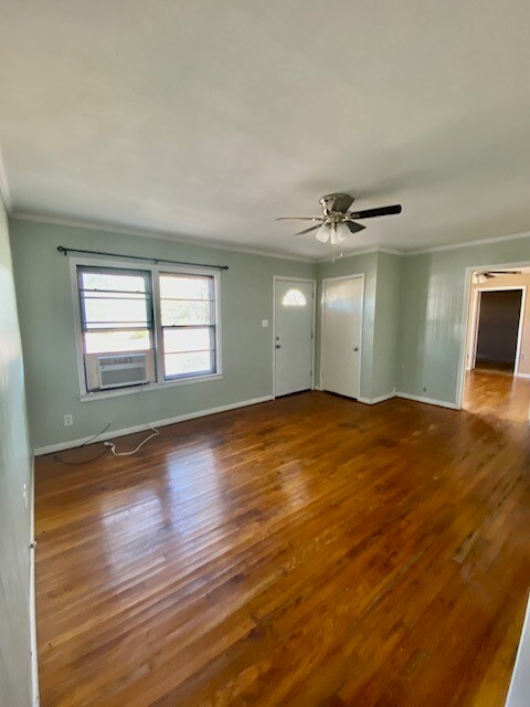 interior space with ceiling fan, crown molding, wood-type flooring, and cooling unit