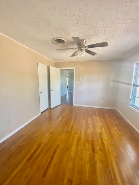 unfurnished room with ceiling fan, hardwood / wood-style flooring, and a textured ceiling