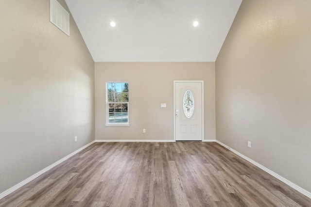 foyer entrance with high vaulted ceiling and light wood-type flooring