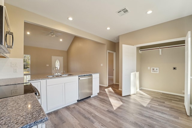 kitchen with light stone counters, stainless steel appliances, sink, and white cabinets