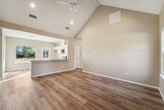 unfurnished living room featuring wood-type flooring, ceiling fan, and high vaulted ceiling