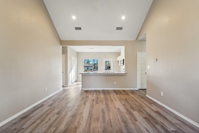 unfurnished living room featuring high vaulted ceiling and light wood-type flooring