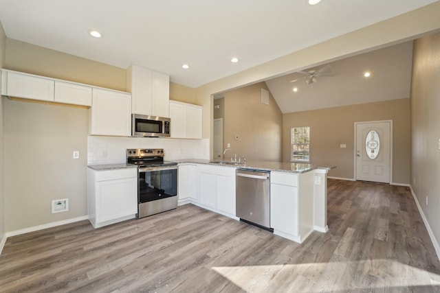 kitchen with lofted ceiling, sink, white cabinets, kitchen peninsula, and stainless steel appliances