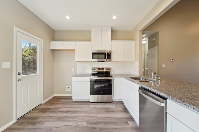 kitchen featuring sink, white cabinetry, light stone counters, light wood-type flooring, and stainless steel appliances