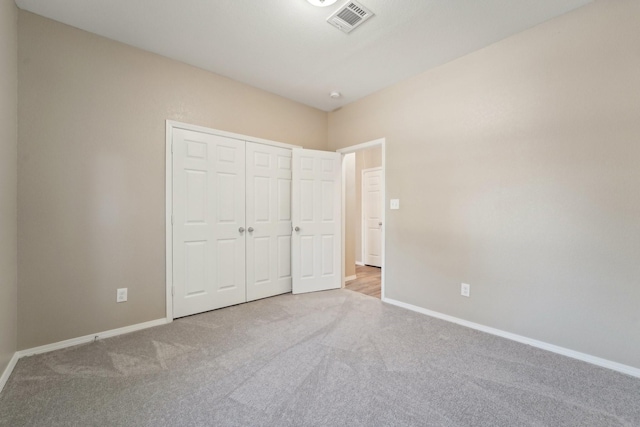 unfurnished bedroom featuring light carpet and a closet