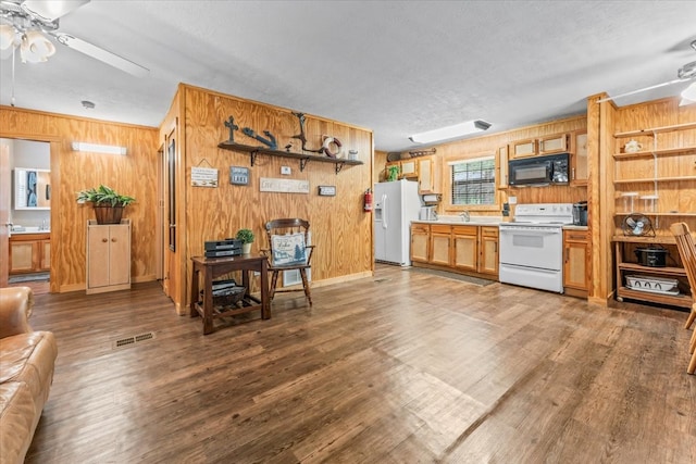 kitchen featuring wooden walls, white appliances, ceiling fan, and dark hardwood / wood-style floors