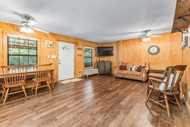 living room with hardwood / wood-style flooring, wooden walls, and a textured ceiling