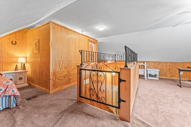 bedroom with lofted ceiling, wood walls, a textured ceiling, and carpet flooring