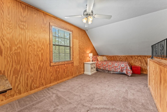 carpeted bedroom featuring vaulted ceiling, ceiling fan, and wood walls