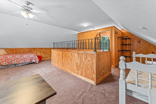 bedroom featuring ceiling fan, lofted ceiling, a textured ceiling, wooden walls, and carpet floors