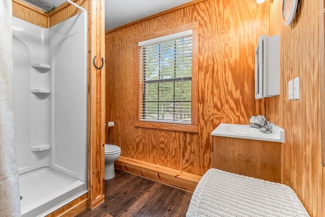 bathroom featuring a shower, vanity, wood walls, toilet, and hardwood / wood-style floors