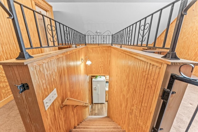 stairway featuring carpet and wooden walls